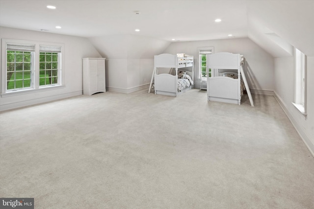 interior space with light carpet, plenty of natural light, and vaulted ceiling