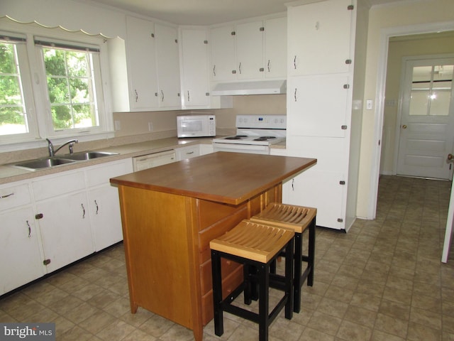 kitchen with white cabinets, a center island, white appliances, and sink