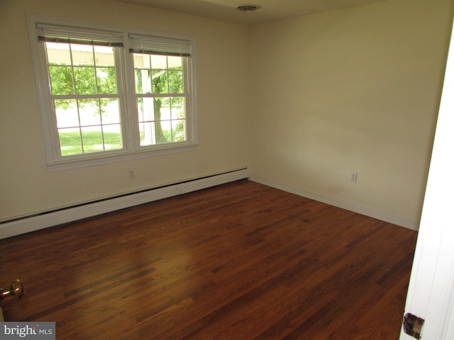 empty room featuring baseboard heating and dark wood-type flooring