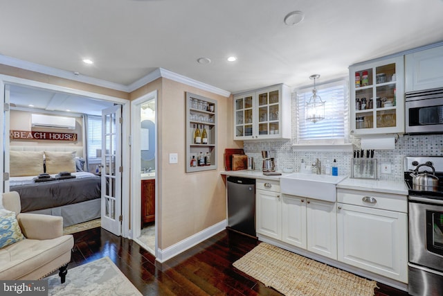 kitchen featuring stainless steel appliances, a wall unit AC, dark wood-type flooring, sink, and pendant lighting