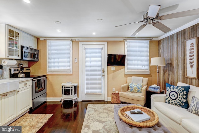 living room with ceiling fan, crown molding, and dark wood-type flooring