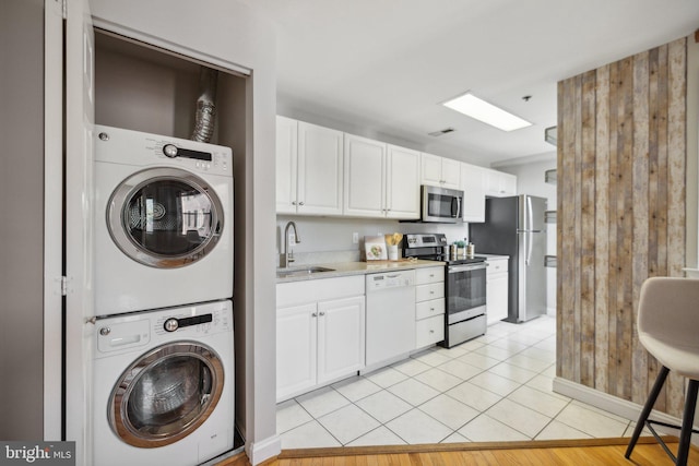 kitchen featuring white cabinets, sink, appliances with stainless steel finishes, and stacked washer and clothes dryer