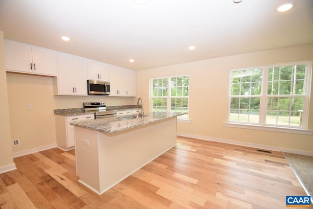 kitchen featuring light hardwood / wood-style floors, white cabinetry, an island with sink, and appliances with stainless steel finishes