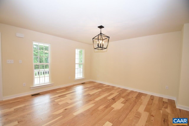 spare room featuring a notable chandelier and light hardwood / wood-style floors