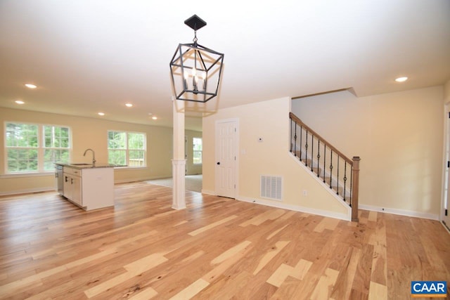 interior space featuring light hardwood / wood-style floors, ornate columns, sink, and a chandelier