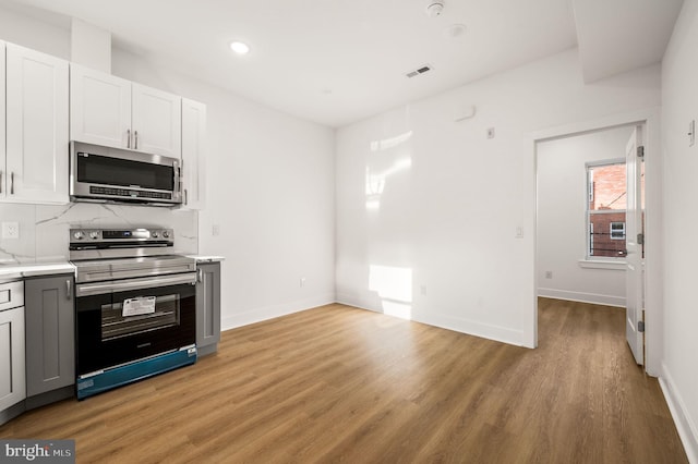 kitchen with gray cabinetry, light hardwood / wood-style flooring, white cabinets, and appliances with stainless steel finishes