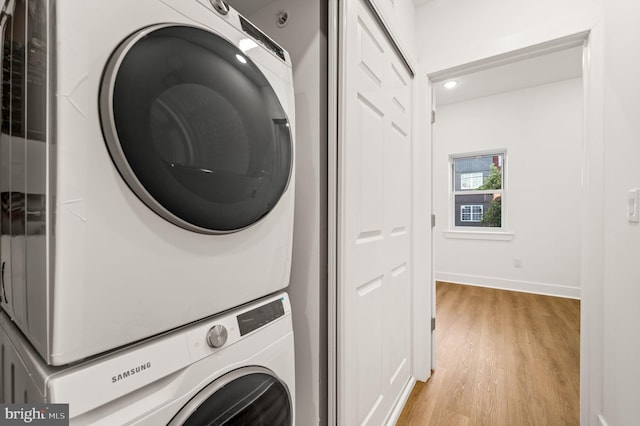 clothes washing area featuring light hardwood / wood-style floors and stacked washer and clothes dryer