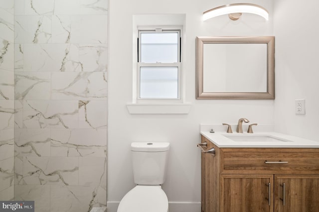 bathroom with a tile shower, vanity, and toilet