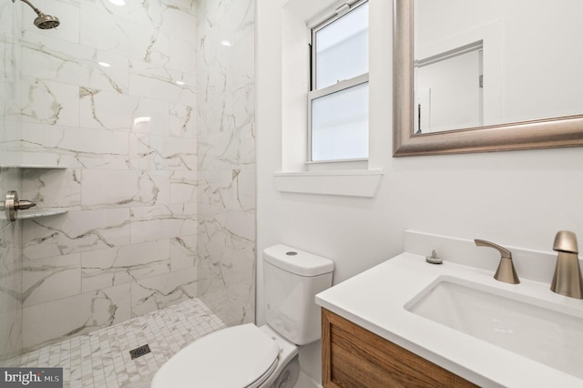 bathroom featuring toilet, plenty of natural light, vanity, and tiled shower