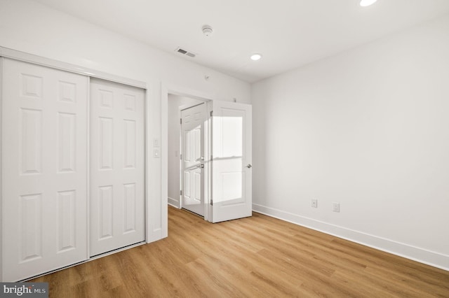 unfurnished bedroom with a closet and light hardwood / wood-style floors