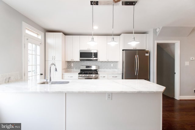 kitchen featuring white cabinetry, sink, decorative light fixtures, and appliances with stainless steel finishes