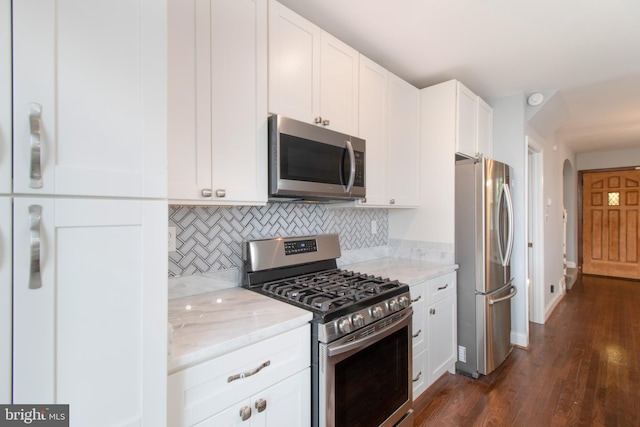 kitchen with light stone countertops, dark hardwood / wood-style flooring, tasteful backsplash, stainless steel appliances, and white cabinets