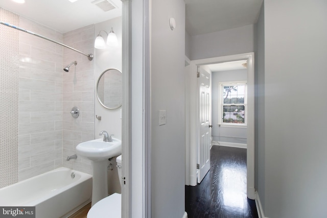 full bathroom featuring hardwood / wood-style flooring, tiled shower / bath combo, toilet, and sink