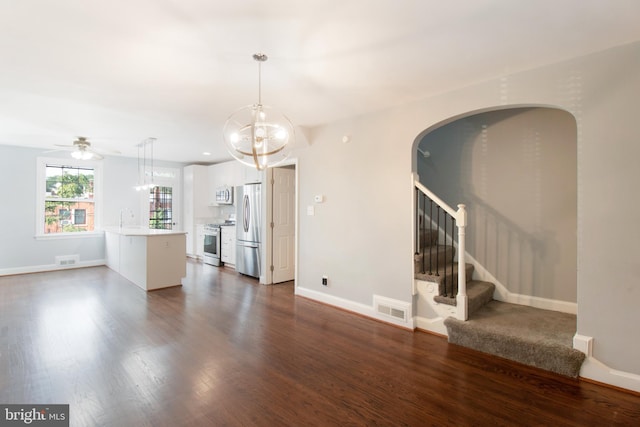 unfurnished living room featuring sink, dark wood-type flooring, and ceiling fan with notable chandelier