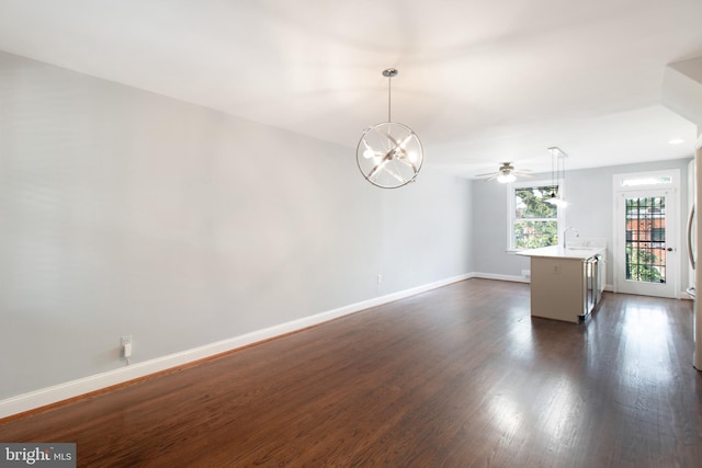 unfurnished room featuring sink, dark wood-type flooring, and ceiling fan with notable chandelier