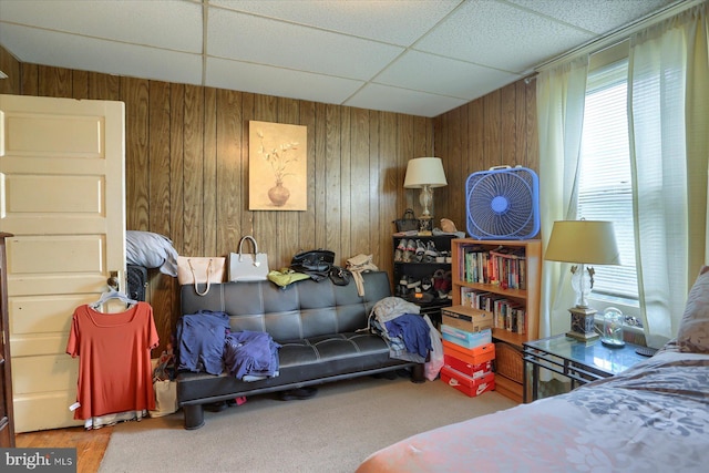 bedroom with a paneled ceiling and wood walls