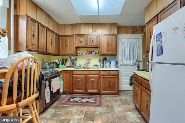 kitchen featuring white fridge, a drop ceiling, and sink