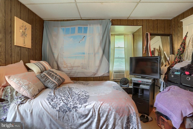 bedroom with a drop ceiling, cooling unit, and wood walls