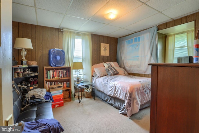 bedroom featuring a paneled ceiling, wooden walls, and carpet