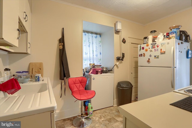 kitchen featuring sink, crown molding, white fridge, white cabinetry, and washer / clothes dryer