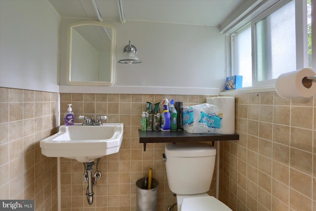 bathroom with toilet and tile walls