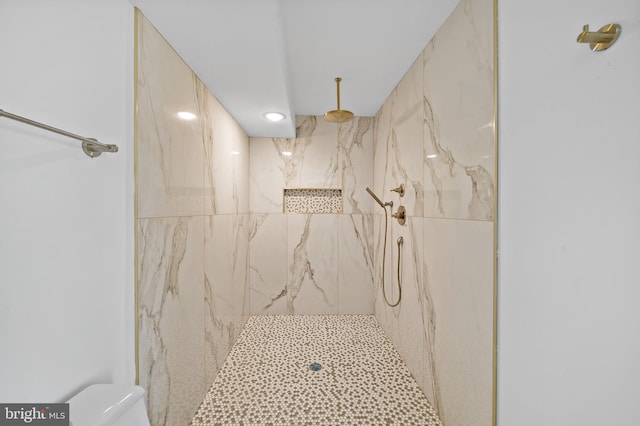 bathroom with a tile shower, toilet, and tile walls