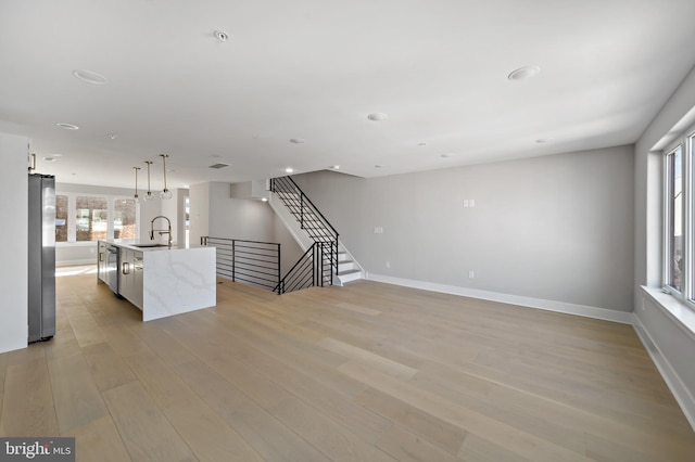 unfurnished living room featuring sink and light hardwood / wood-style flooring