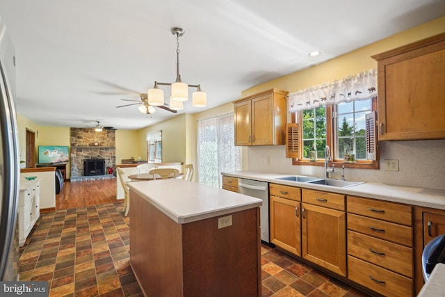 kitchen with appliances with stainless steel finishes, ceiling fan, sink, a fireplace, and a kitchen island