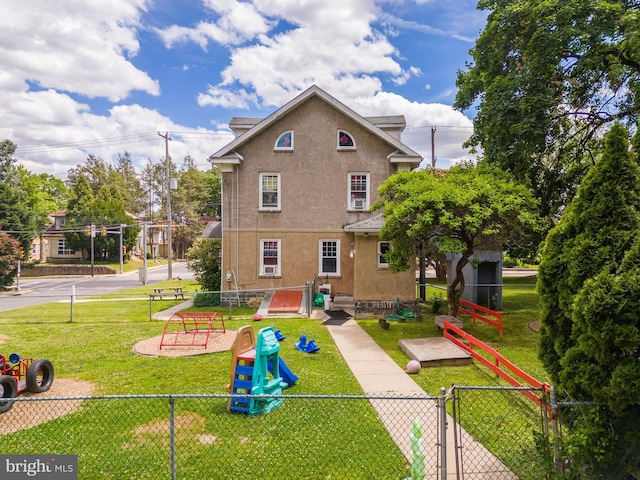 back of property with a lawn and a playground