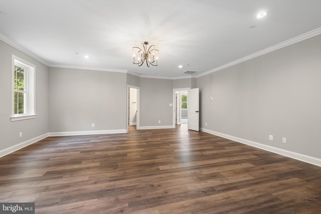 spare room with crown molding, a healthy amount of sunlight, dark hardwood / wood-style floors, and a notable chandelier