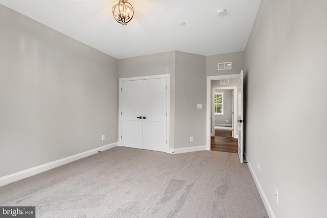 unfurnished bedroom featuring carpet, a chandelier, and a closet