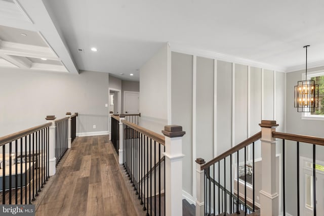 hallway with dark hardwood / wood-style flooring, coffered ceiling, crown molding, a notable chandelier, and beamed ceiling