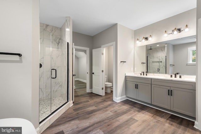 bathroom with toilet, vanity, a shower with shower door, and hardwood / wood-style flooring