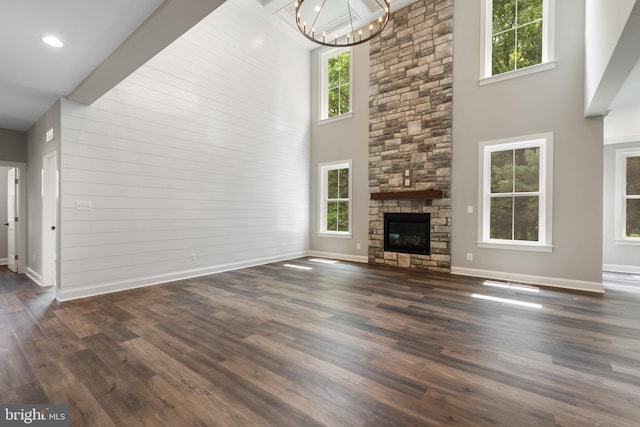 unfurnished living room featuring plenty of natural light, a towering ceiling, and dark wood-type flooring