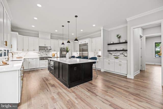 kitchen featuring built in appliances, light countertops, white cabinetry, and under cabinet range hood