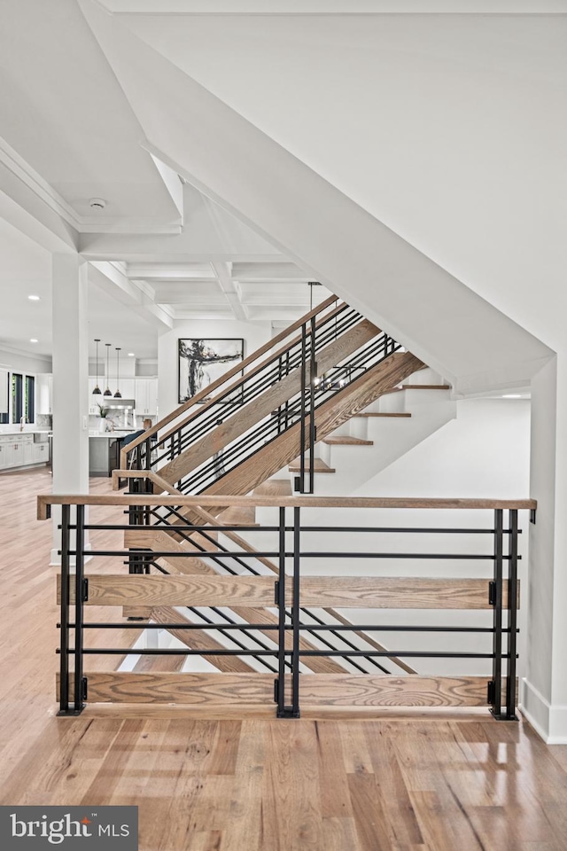 stairway with wood finished floors and beam ceiling