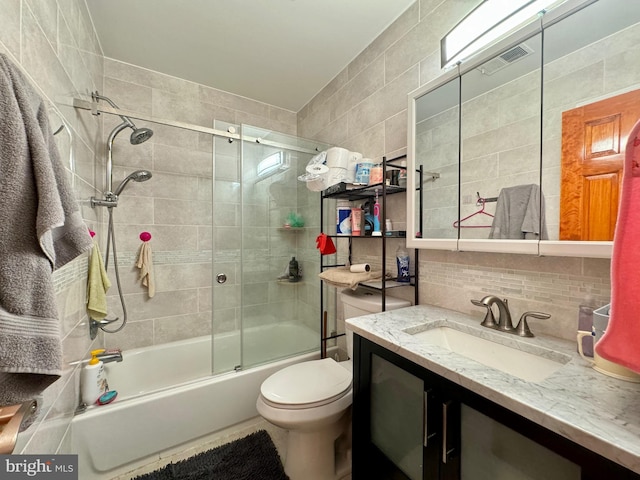 full bathroom with shower / bath combination with glass door, vanity, tasteful backsplash, and tile walls