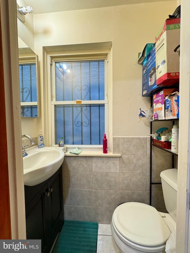 bathroom featuring tile patterned flooring, vanity, tile walls, and toilet