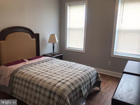 bedroom with dark hardwood / wood-style flooring and multiple windows