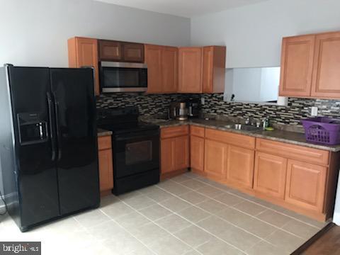 603 Allendale St, Baltimore, MD 21229 - kitchen with black appliances, backsplash, a sink, dark countertops, and brown cabinetry