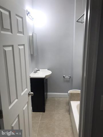 bathroom with tile patterned floors, vanity, and a tub to relax in