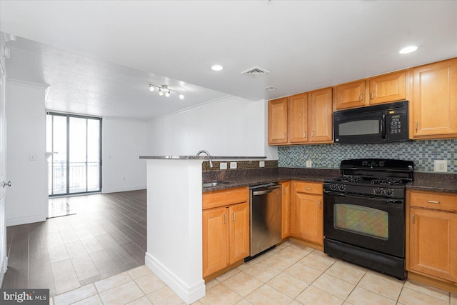 kitchen featuring light tile patterned floors, crown molding, dark stone countertops, black appliances, and kitchen peninsula