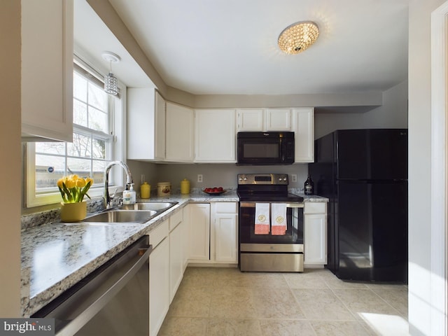 kitchen featuring hanging light fixtures, light stone countertops, black appliances, white cabinets, and sink