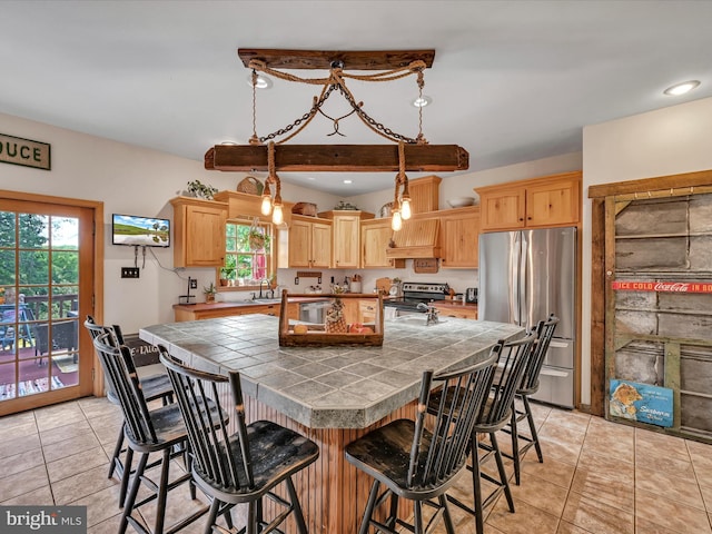 kitchen featuring appliances with stainless steel finishes, light brown cabinets, pendant lighting, a kitchen island, and a breakfast bar area