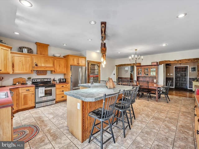 kitchen with hanging light fixtures, stainless steel appliances, a notable chandelier, a kitchen bar, and a kitchen island