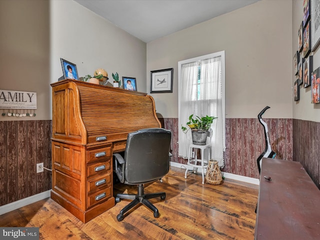 office area with hardwood / wood-style floors and wooden walls