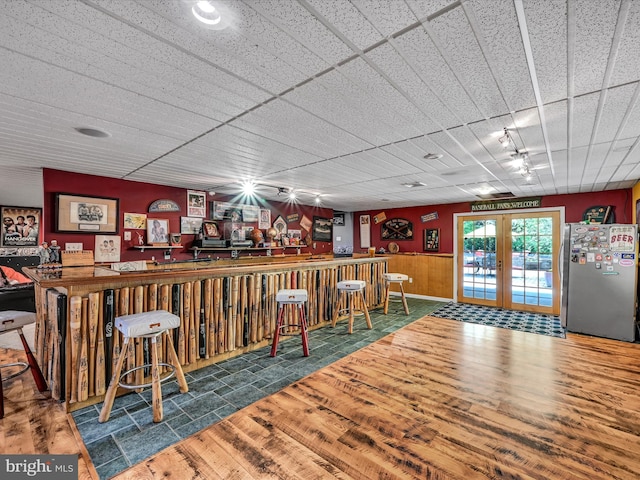 bar with stainless steel fridge, french doors, track lighting, and hardwood / wood-style flooring