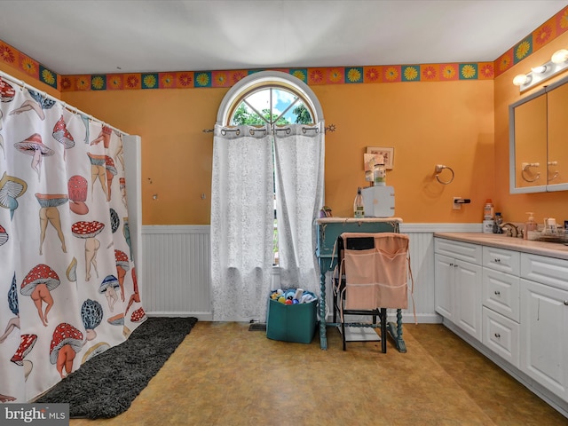 bathroom with a shower with shower curtain, vanity, and wooden walls