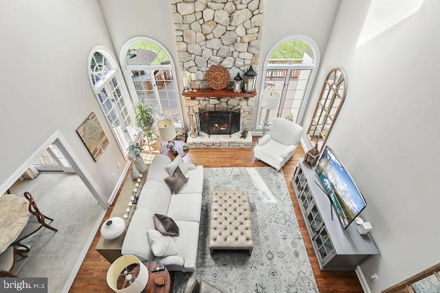 living room featuring a wealth of natural light, a fireplace, wood-type flooring, and a high ceiling