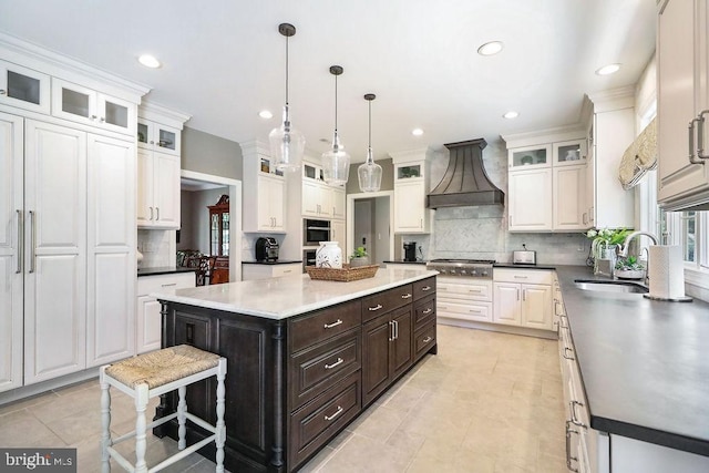 kitchen featuring a center island, white cabinetry, sink, and custom range hood